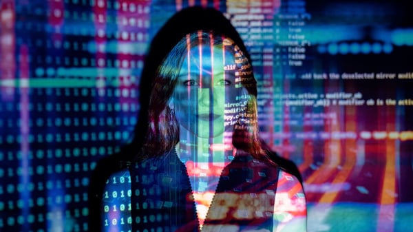 Woman stands illuminated by a colorful code reflection