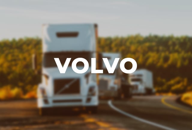 Volvo written on top of a blurred image of trucks on the road
