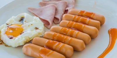 a picture of a plate with sausages, eggs and ham