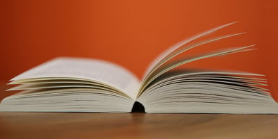 An open book on a table with orange background