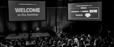 Seminar attendees sitting and watching a welcome screen in the Nordic Business Forum