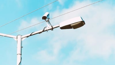 security camera attached in a street lamp with sky background